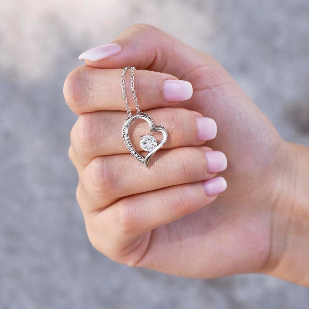 Heart necklace with cubic zirconia for wife in a hand with neutral nails.